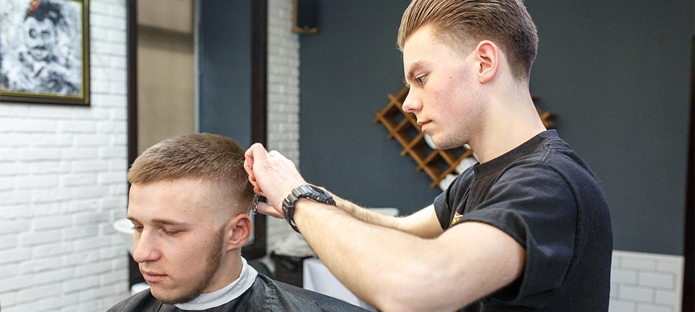 barber in training cutting taper fade haircut