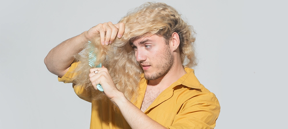 Hair loss blonde man with a comb and problem hair. Hairloss and hairs problems. Sad guy with damaged hair combing hairs. Alopecia, dandruff. Tangled, frizzy, messy hair.